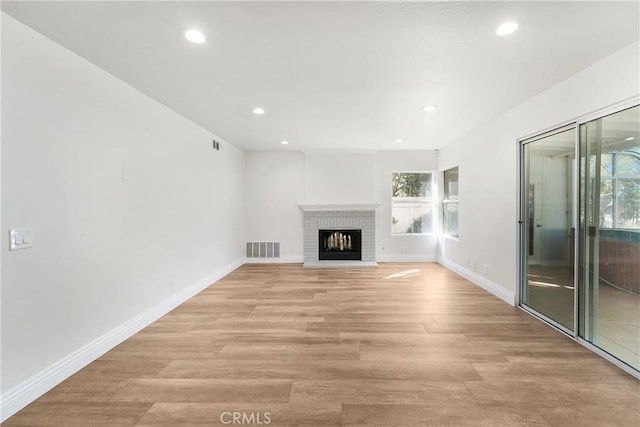 unfurnished living room featuring a wealth of natural light, a fireplace, and light hardwood / wood-style floors