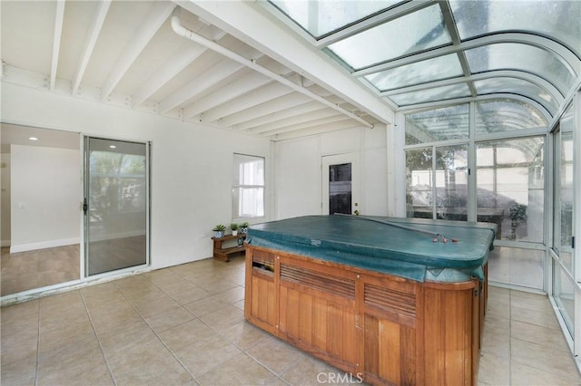 sunroom featuring beamed ceiling and a skylight