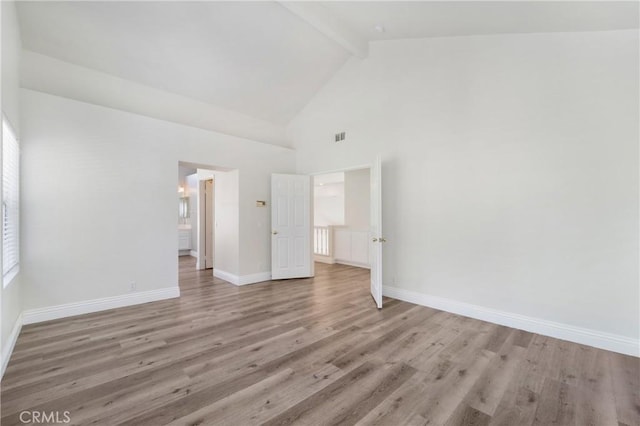 spare room with high vaulted ceiling, beamed ceiling, and light wood-type flooring