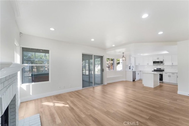 unfurnished living room with sink, a fireplace, and light hardwood / wood-style floors