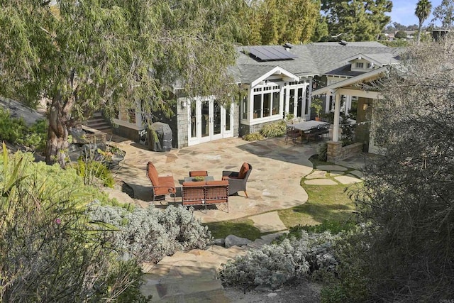 rear view of property with an outdoor living space, a patio, solar panels, and french doors