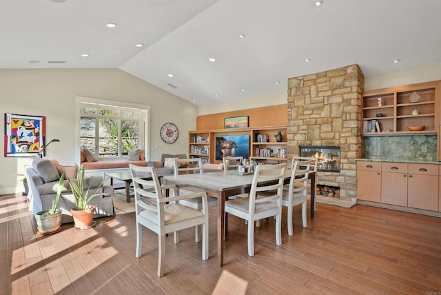 dining space with lofted ceiling, light wood-type flooring, and a fireplace