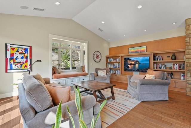 living room featuring lofted ceiling and light hardwood / wood-style floors