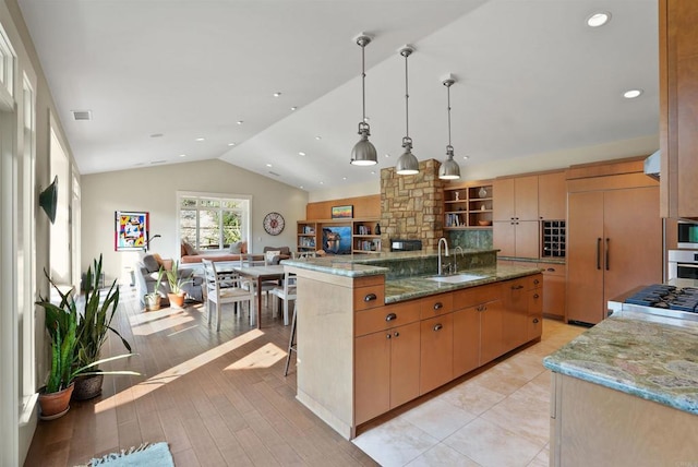 kitchen with decorative light fixtures, lofted ceiling, sink, a large island, and light stone countertops