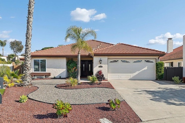 view of front facade featuring driveway, a tile roof, an attached garage, fence, and stucco siding