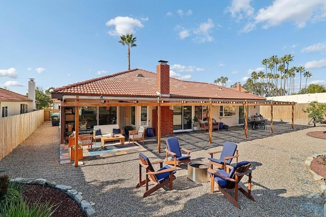 back of property featuring a tile roof, an outdoor living space with a fire pit, a patio, and a fenced backyard