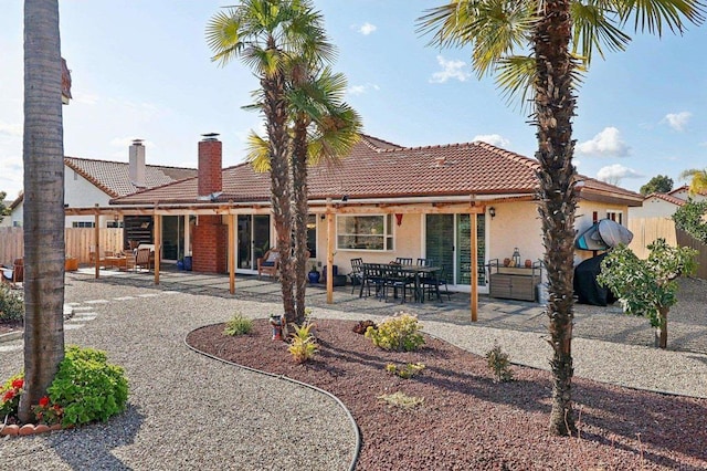 rear view of property featuring a patio, fence, a tiled roof, and stucco siding