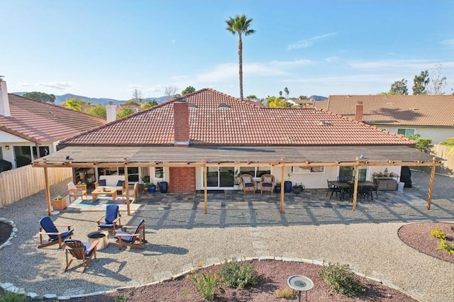 rear view of house featuring fence, a patio, and a tiled roof