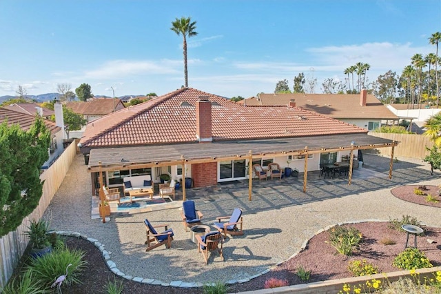 back of house featuring an outdoor living space with a fire pit, a fenced backyard, a patio, and a tiled roof