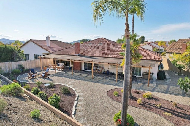 rear view of property with a fenced backyard, a tile roof, and a patio