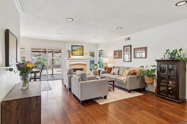 living area featuring visible vents, dark wood-type flooring, crown molding, a fireplace, and recessed lighting