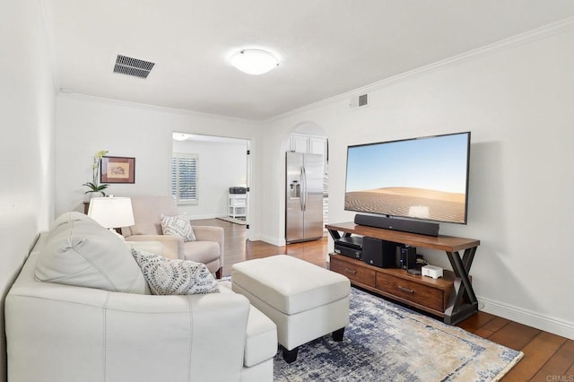 living room with baseboards, crown molding, visible vents, and wood finished floors