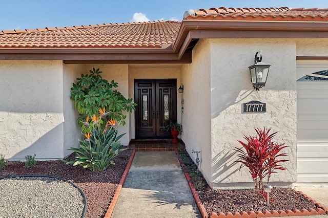 entrance to property with an attached garage and stucco siding