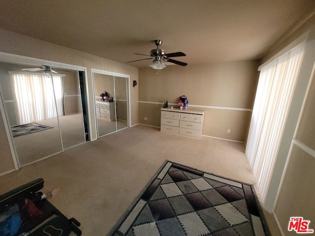 unfurnished bedroom featuring carpet, two closets, and ceiling fan