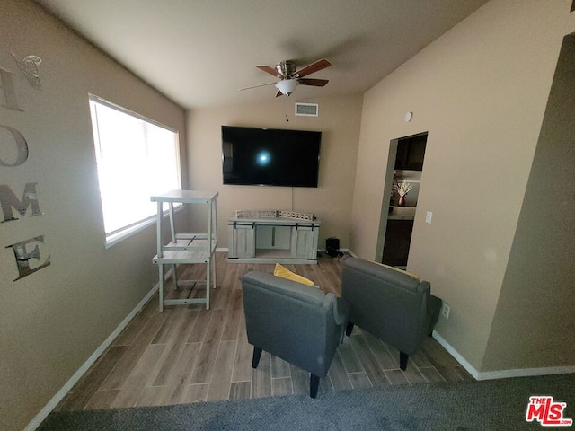 living room with vaulted ceiling, ceiling fan, and light wood-type flooring