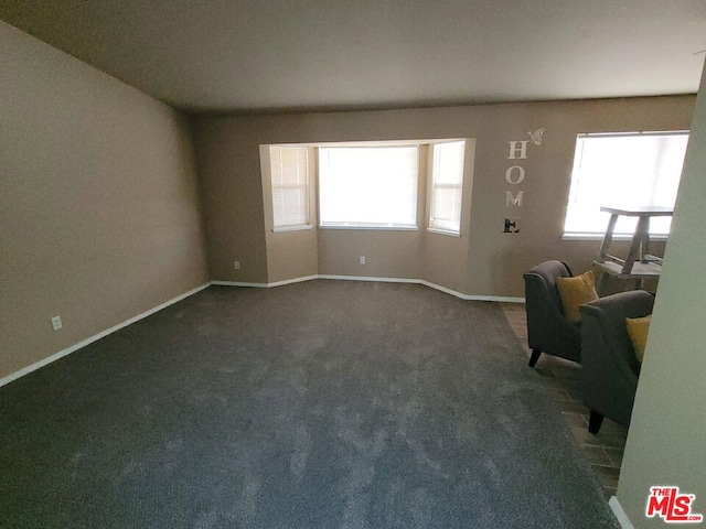 unfurnished living room featuring plenty of natural light and dark colored carpet