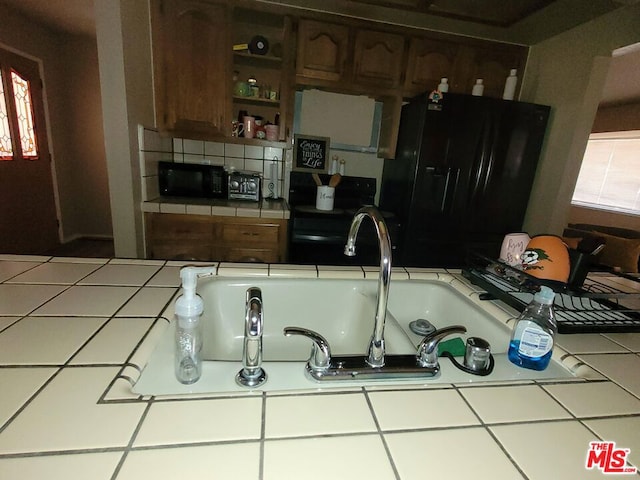 kitchen with tile countertops, decorative backsplash, and black appliances