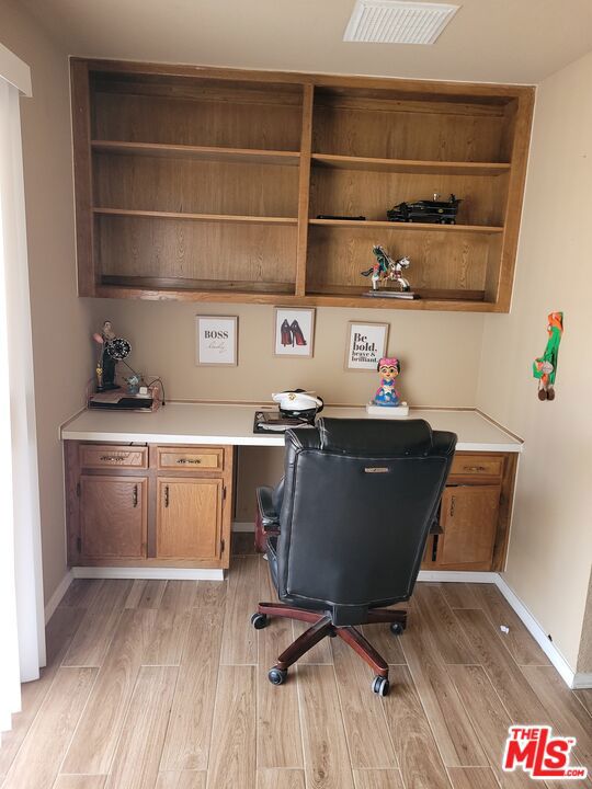 office space featuring built in desk and light hardwood / wood-style floors