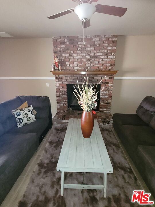 living room with ceiling fan and a brick fireplace