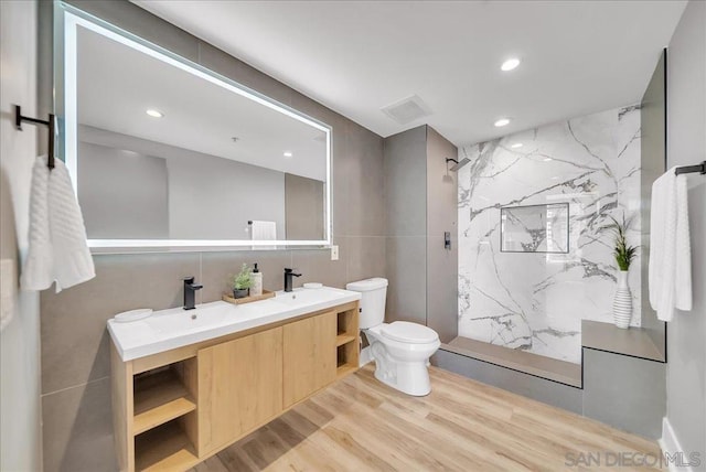 bathroom with tile walls, vanity, hardwood / wood-style flooring, and walk in shower