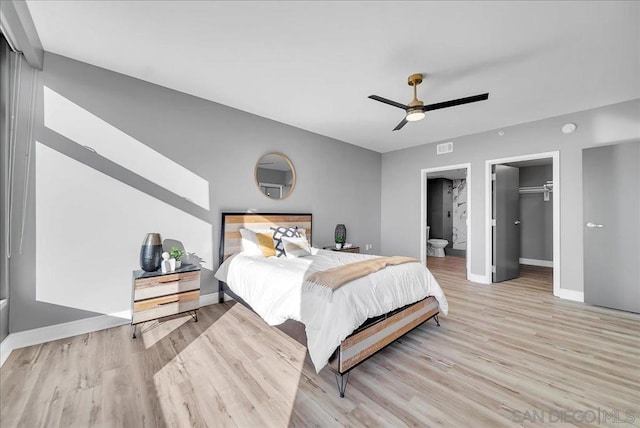 bedroom with ensuite bath, light hardwood / wood-style flooring, ceiling fan, a walk in closet, and a closet