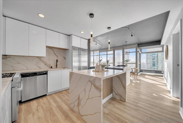 kitchen featuring white cabinetry, hanging light fixtures, backsplash, stainless steel appliances, and a center island