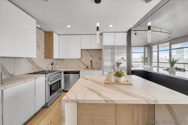 kitchen featuring a kitchen island, pendant lighting, sink, white cabinets, and high end appliances