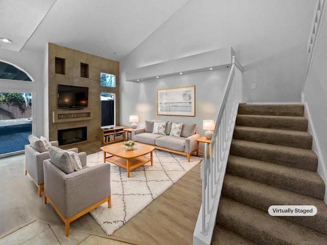 living room with a healthy amount of sunlight, high vaulted ceiling, and a tile fireplace