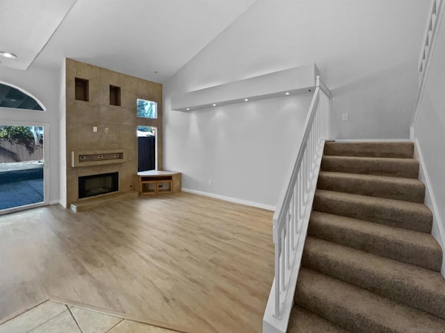 unfurnished living room with a high ceiling, a healthy amount of sunlight, and a large fireplace