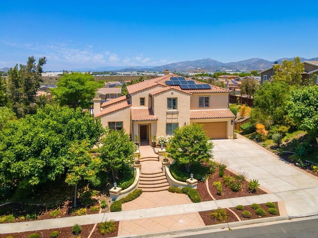 mediterranean / spanish-style house featuring a garage, a mountain view, and solar panels