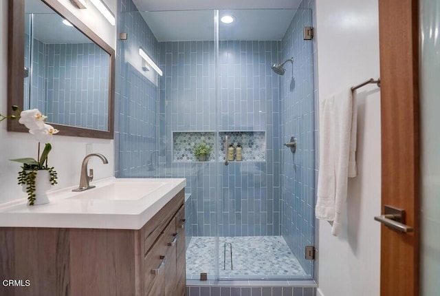 bathroom featuring a shower with door and vanity