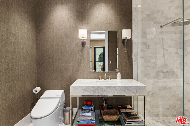 bathroom with a tile shower, sink, and toilet