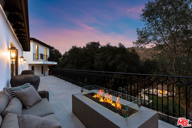 patio terrace at dusk with a balcony and an outdoor living space with a fire pit