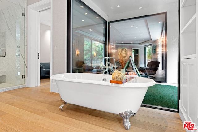 bathroom with hardwood / wood-style flooring and independent shower and bath