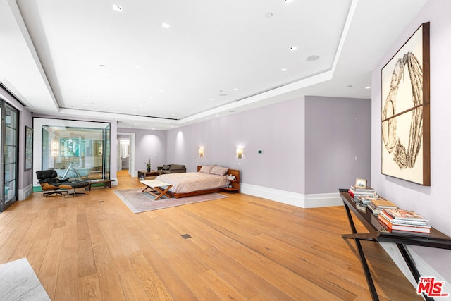 bedroom featuring a raised ceiling and light wood-type flooring