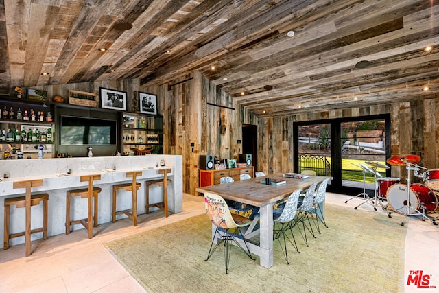 dining area featuring light tile patterned flooring, indoor bar, wood ceiling, and wood walls