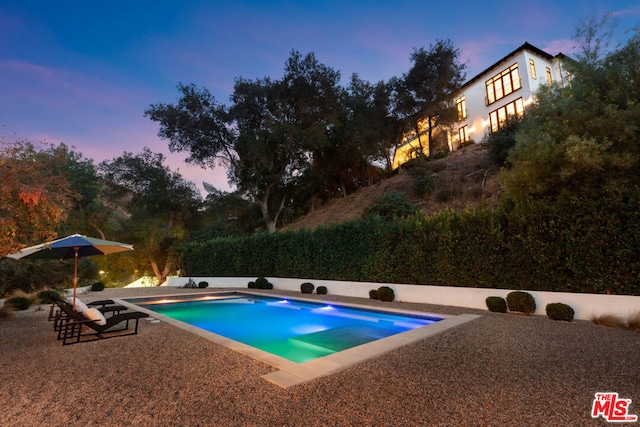 pool at dusk with a patio area