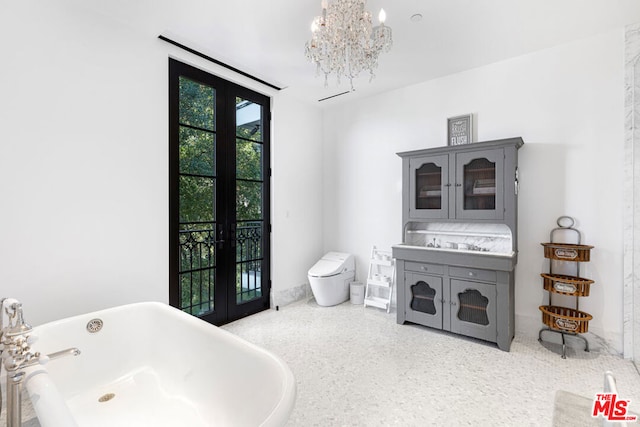 bathroom with toilet, a notable chandelier, a bathtub, and french doors