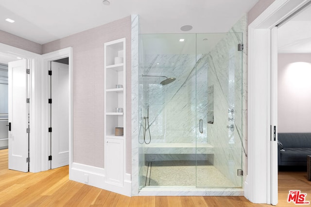 bathroom featuring hardwood / wood-style flooring, a shower with door, and built in shelves