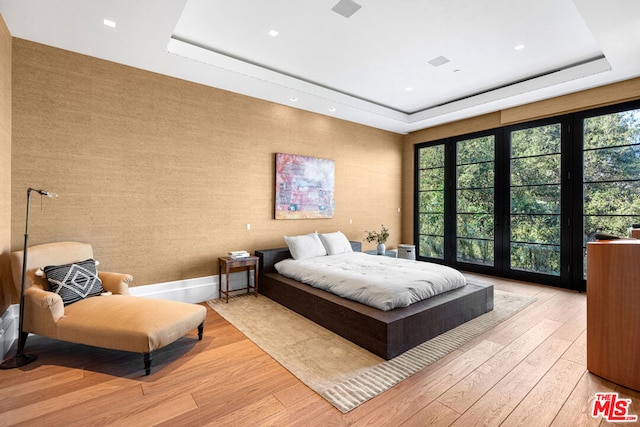 bedroom featuring light wood-type flooring and a tray ceiling