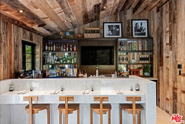 bar with lofted ceiling, wood ceiling, and wood walls