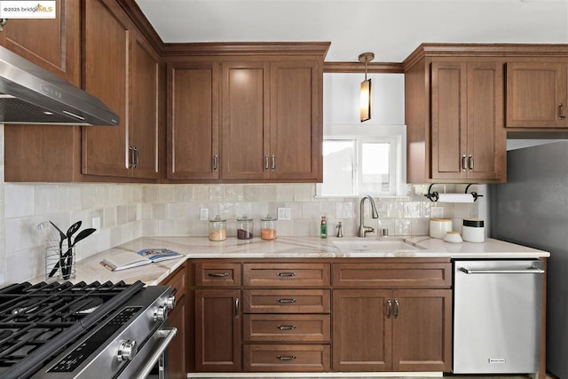 kitchen featuring wall chimney exhaust hood, sink, pendant lighting, stainless steel appliances, and backsplash