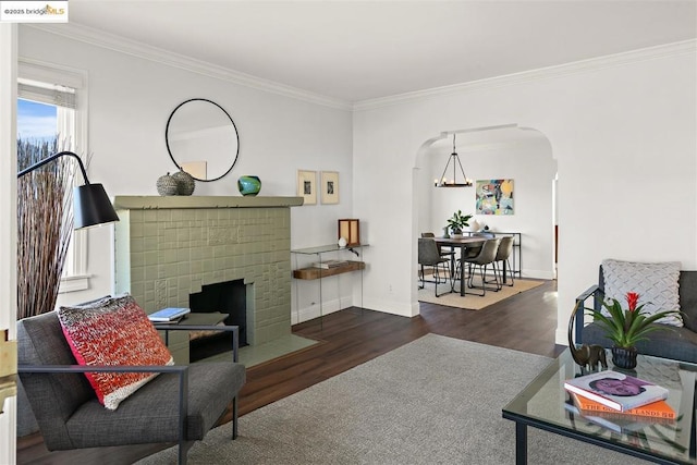 living room with a notable chandelier, crown molding, a fireplace, and dark hardwood / wood-style flooring