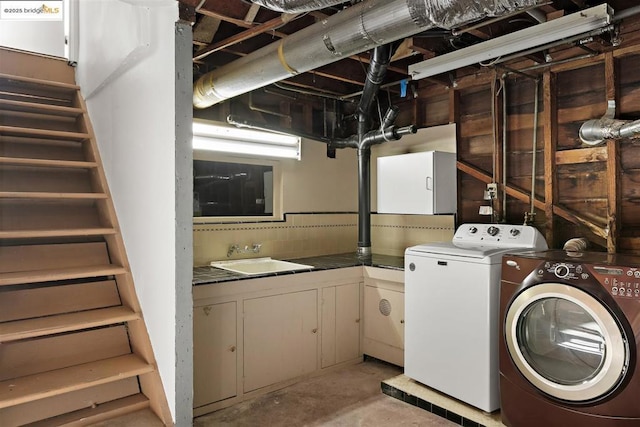 laundry room with cabinets, washer and clothes dryer, and sink