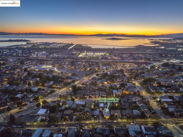 aerial view at dusk featuring a water view