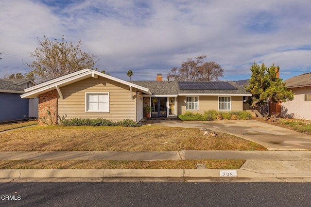 ranch-style house with a front lawn and solar panels