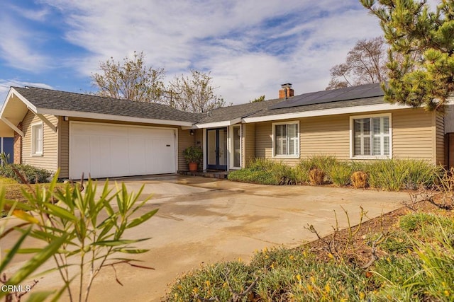 ranch-style home featuring a garage and solar panels