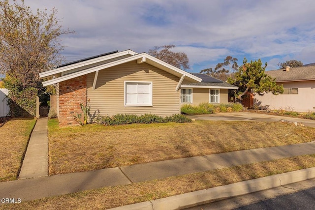 ranch-style home featuring a front lawn and solar panels