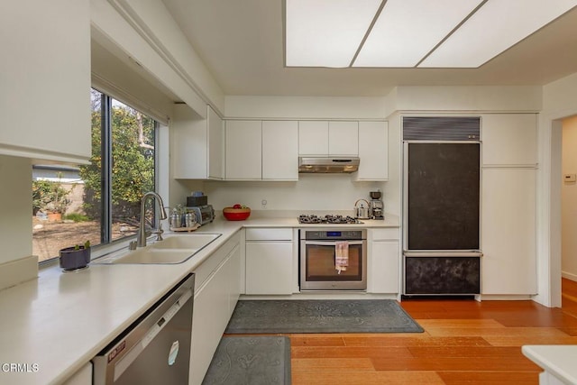 kitchen featuring stainless steel appliances, sink, white cabinets, and light wood-type flooring