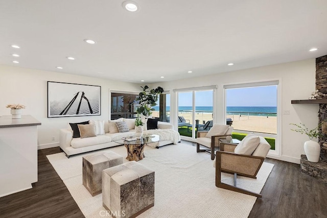 living room featuring a view of the beach, dark hardwood / wood-style floors, and a water view